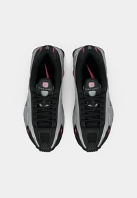 Para czarno-szarych trampek Nike Shox z różowymi akcentami widziana z góry na białym tle.