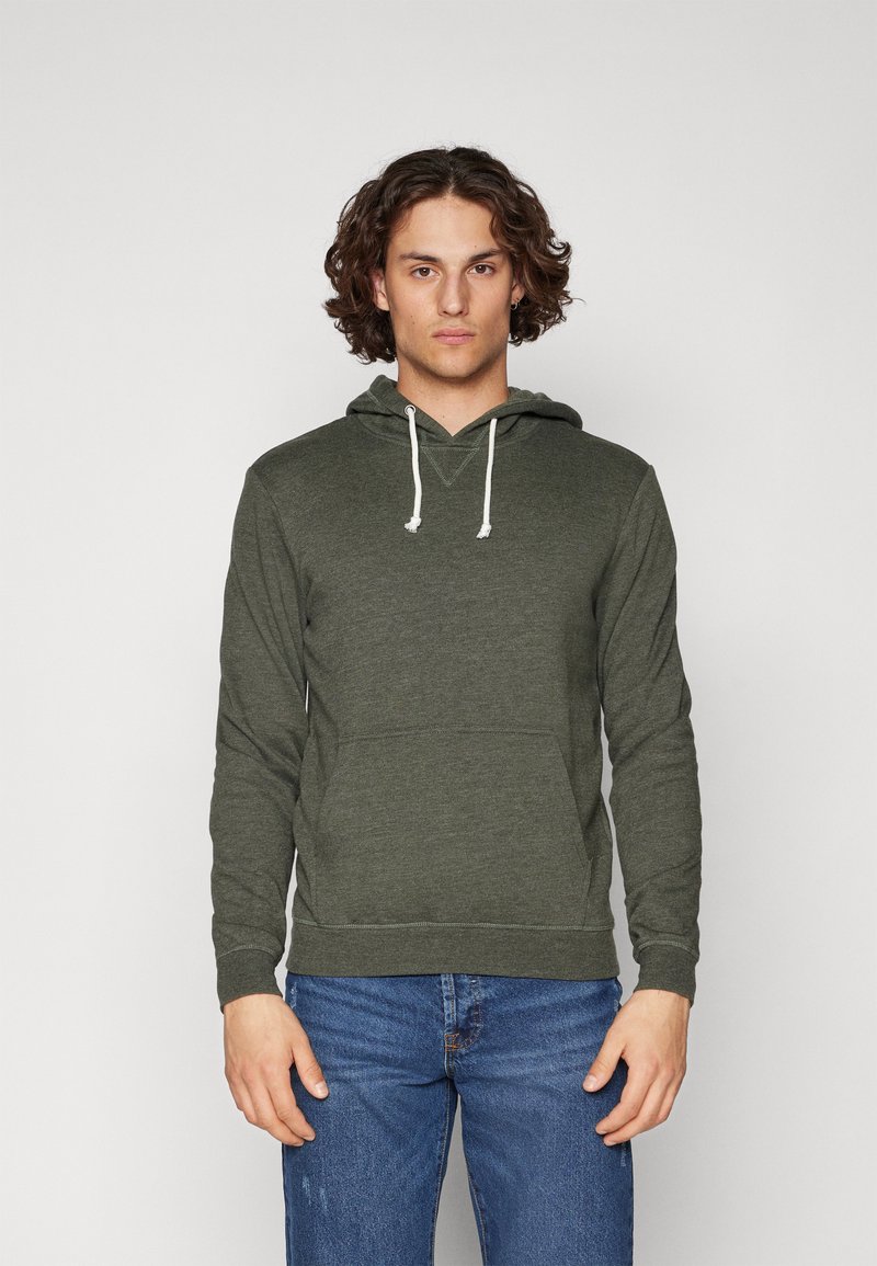 Sudadera verde oliva con un bolsillo tipo canguro, capucha ajustable con cordones y puños acanalados. La tela parece suave y tiene un corte informal.