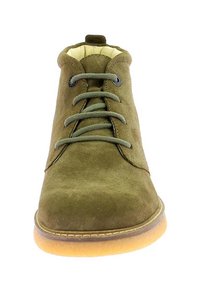 Bottine en daim vert olive avec bout rond, lacets à l'avant et doublure beige. Dispose d'une semelle en caoutchouc beige et de lacets ton sur ton.