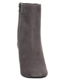 Harmaa mokkanahkainen nilkkaboots, jossa on tyylikäs, kapeneva muotoilu ja sivu vetoketjukiinnitys. Materiaali on pehmeä ja pinnaltaan sileä.