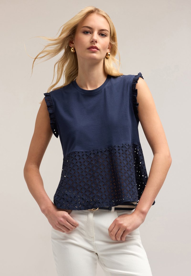 Top blu navy a maniche corte con una parte superiore liscia e una sezione inferiore caratterizzata da un motivo a rete diamantata testurizzato. Dettagli con bordo delle maniche arricciato.