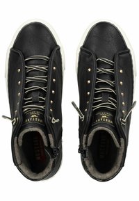 Baskets montantes en cuir noir avec des clous métalliques, semelle en caoutchouc blanche et doublure beige. Elles disposent de lacets et de fermetures éclair latérales doubles pour un enfilage facile.