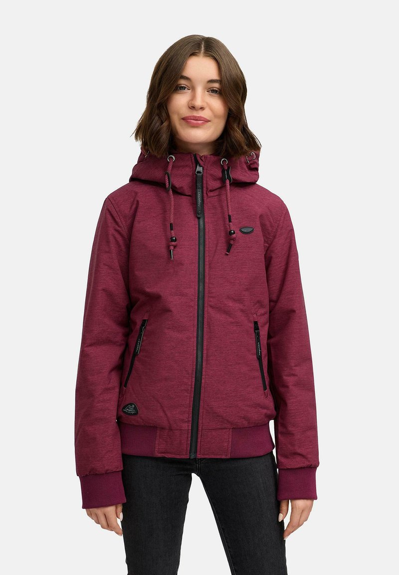 Burgunderrød hettejakke med glidelås foran, to sidelommer og ribbestrikkede mansjetter. Har snorer for justering og et teksturert stoff.