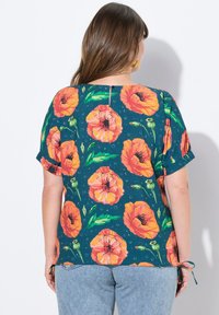 T-shirt med kortærmer i mørkeblå baggrund, prydet med store orange valmueblomster og grønne blade, samt en knapdetalje på ryggen.