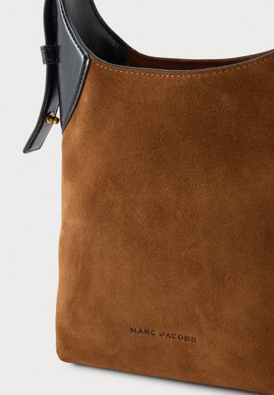 Крупен план на кафява велурена чанта за рамо Marc Jacobs с черни кожени кантове, катарама на презрамката и шев по ръба.