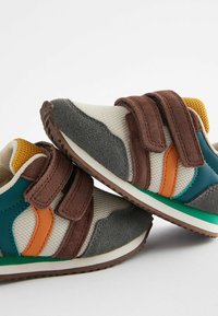 Dziecięce sneakersy z brązowymi rzepami, szare, w kolorze turkusowym i pomarańczowym akcentami, teksturowana tkanina oraz gumowa podeszwa z zielonym akcentem.