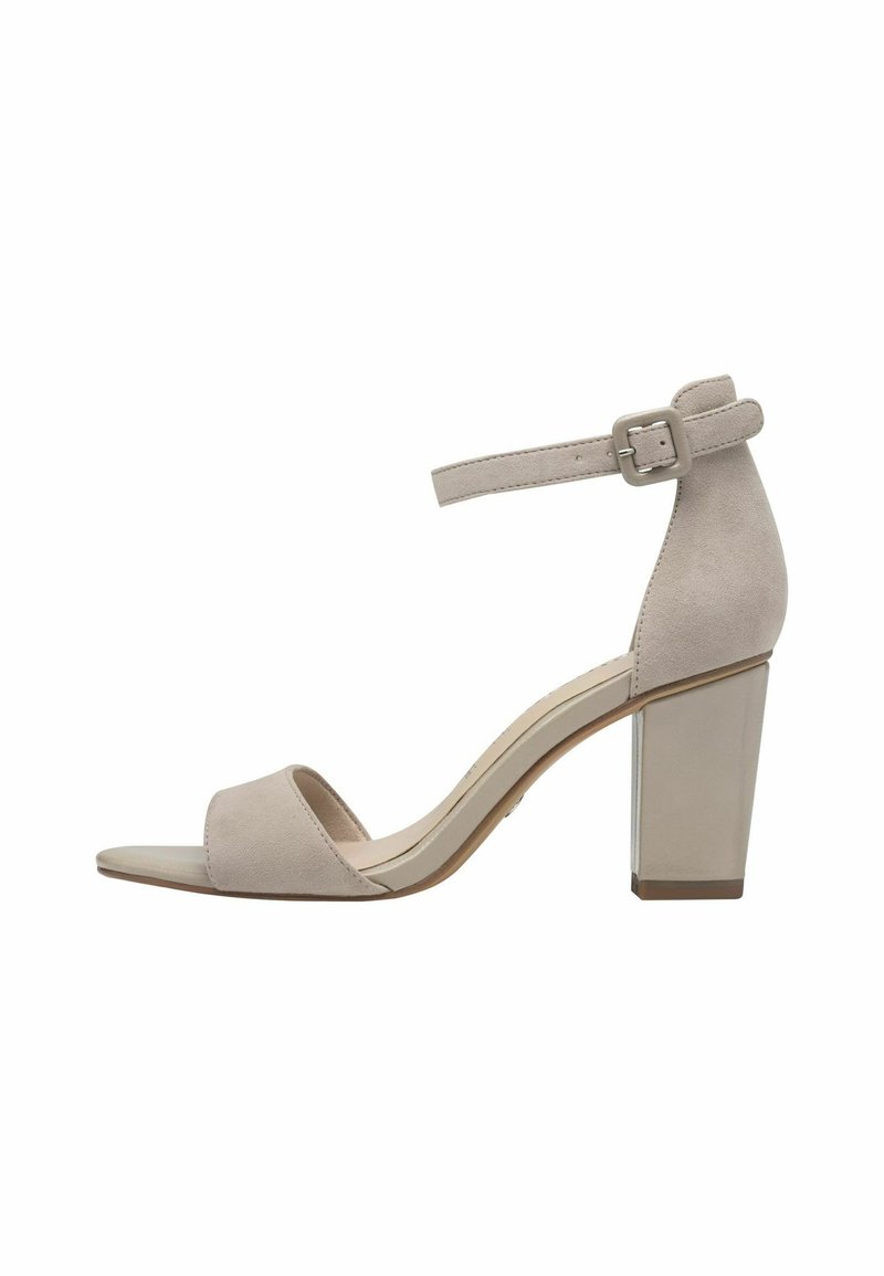 Beige suede high-heeled sandal with an ankle strap, open toe, and a chunky heel featuring a metallic accent. Smooth texture and minimal design.