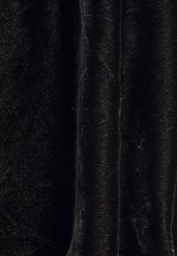 Černý sametový materiál s jemnou texturou, s hladkým povrchem a subtilním leskem, splývá tak, aby ukázal záhyby a hloubku.