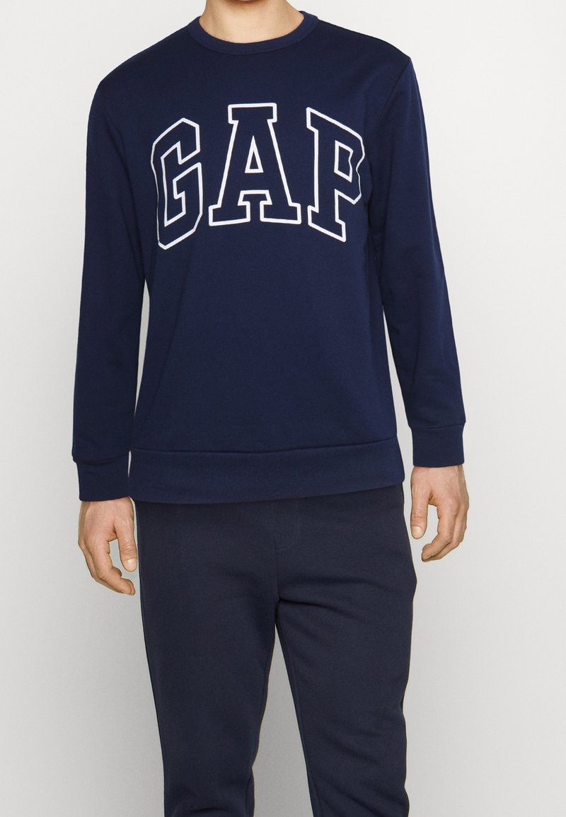 Sweat-shirt bleu marine à col rond avec le logo blanc "GAP". Confectionné dans un tissu doux, il présente des manches longues et des poignets côtelés.
