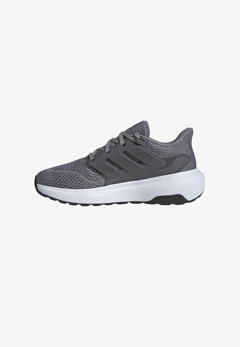 Scarpa sportiva grigia con tomaia in mesh, tre strisce prominenti, suola bianca ammortizzata e battistrada nero. Presenta un sistema di allacciatura e collare imbottito.