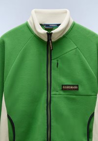 Green fleece jacket with cream collar, navy accents, zippered chest pocket, and logo patch. Features textured fabric and a sporty design.