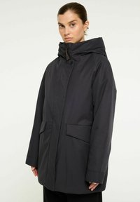 Mörk, vattentät parka med hög krage, som har en frontdragkedja, tryckknappar och två stora sidofickor. Slät textur.