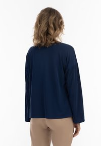 Camicia a maniche lunghe blu navy con una vestibilità rilassata e scollatura tonda, caratterizzata da un tessuto liscio e cuciture delle spalle cadute.