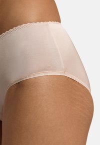 Kombination av bomullshipsterunderkläder i ljusrosa, med en slät textur, vågig elastisk midjeband och kontrasterande sömmar.