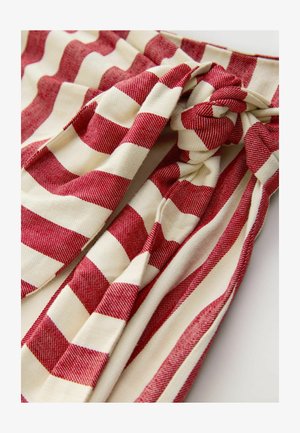 Rot- und cremefarben gestreifter Stoff mit einem geknoteten Design, einer weichen, strukturierten Oberfläche und abwechselnd breiten und schmalen Streifen.