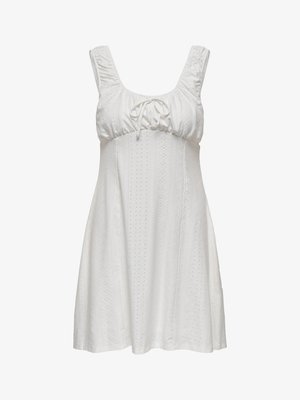 Bijela haljina bez rukava s nabranim izrezom, detaljem za vezanje i teksturiranim materijalom koji sadrži uzorke s rupicama. Rasplinuta silueta s mekim linijama.