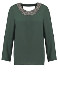 Blouse verte à manches longues avec un col rond orné de perles et une texture lisse, semblable à du satin. Coupe droite simple et absence de motifs visibles.