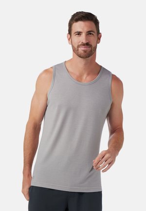 Gray sleeveless tank top with a textured fabric, round neckline, and curved hem. Model is standing, hands relaxed at sides.