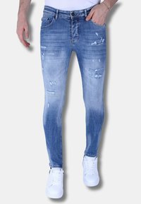 Lichtblauwe denim jeans met een slim fit, met vervaagde gebieden, gescheurde details en een klassiek vijf-pocket ontwerp. Gecombineerd met witte sneakers.