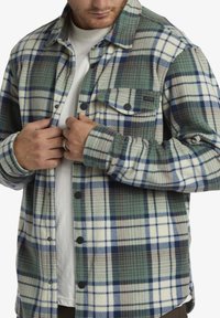 Flanellhemd in den Farben grün, blau und creme, mit einem karierten Muster, Knopfleiste und einer einzelnen Brusttasche. Weicher Stoff.