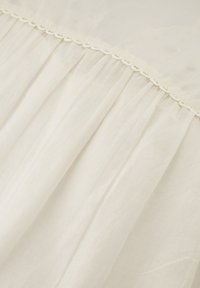 Lichtgewicht, zalmkleurig stof met zachte plooien,Accentuered door delicate kantafwerking langs de bovenkant. Gelaagd, doorschijnend uiterlijk.