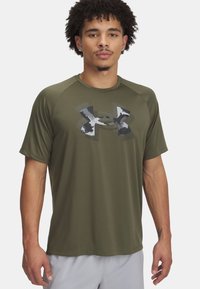 Camiseta atlética de manga corta en verde oliva con un logo de camuflaje de Under Armour en el frente, hecha de un material sintético ligero.