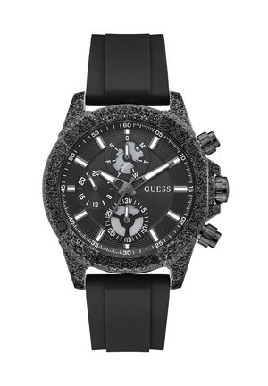Μαύρο ρολόι χειρός Guess με ανάγλυφη στεφάνη, μαύρο καντράν, τρεις υποενδείξεις, λευκούς δείκτες ώρας και μαύρο λουράκι σιλικόνης.