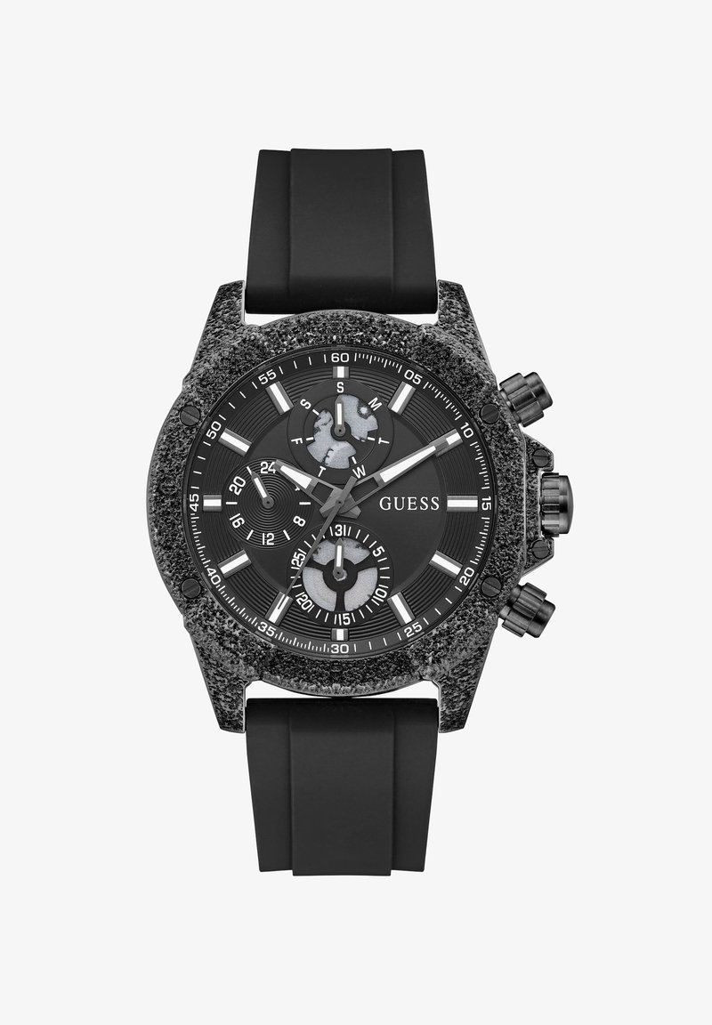 Μαύρο ρολόι χειρός Guess με ανάγλυφη στεφάνη, μαύρο καντράν, τρεις υποενδείξεις, λευκούς δείκτες ώρας και μαύρο λουράκι σιλικόνης.