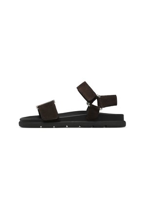 Sandalo piatto nero con due cinturini regolabili in suede sul piede e alla caviglia su una suola strutturata.
