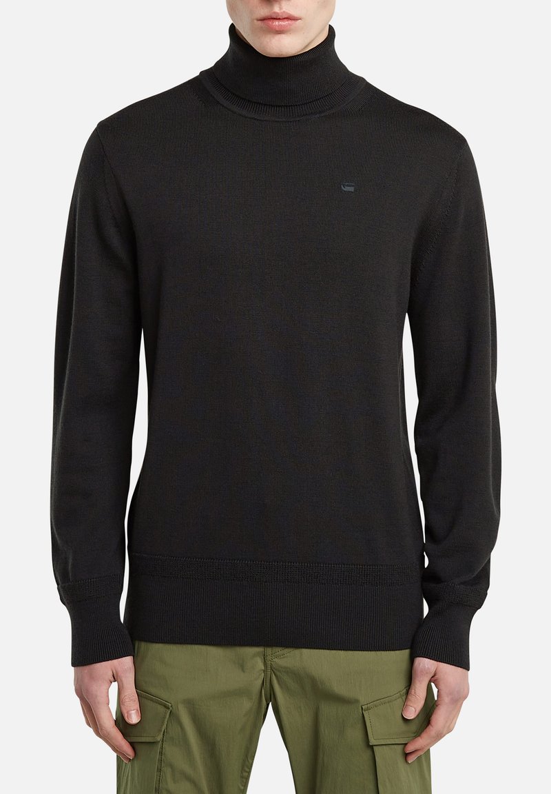 Schwarzer Rollkragenpullover aus geripptem Stoff mit eng anliegenden Ärmeln und feiner Struktur. Verfügt über ein kleines Markenlogo auf der Brust.