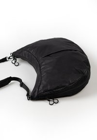 Borsa in tessuto nero a forma di mezzaluna, con cerniere e spallacci regolabili. Texture liscia con dettagli minimi. Design leggero.