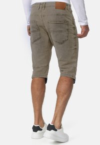 Khaki denim shorts med en normal pasform, der har to baglommer og opsmøgede ben, som afslører et kontrasterende stof. Båret med hvide sneakers.