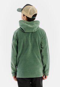 Felpa in pile verde con un grande cappuccio, maniche lunghe e una superficie liscia. La vista posteriore mostra un design semplice e senza hardware visibile.