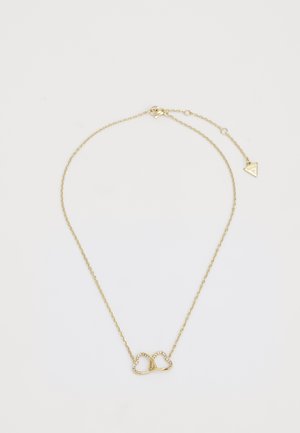 Gouden ketting met een hartvormige hanger waarop kleine, ingebedde edelstenen zijn bevestigd, en een driehoekige charme aan de sluiting.