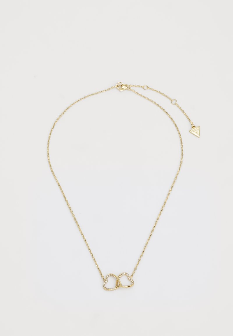 Gouden ketting met een hartvormige hanger waarop kleine, ingebedde edelstenen zijn bevestigd, en een driehoekige charme aan de sluiting.
