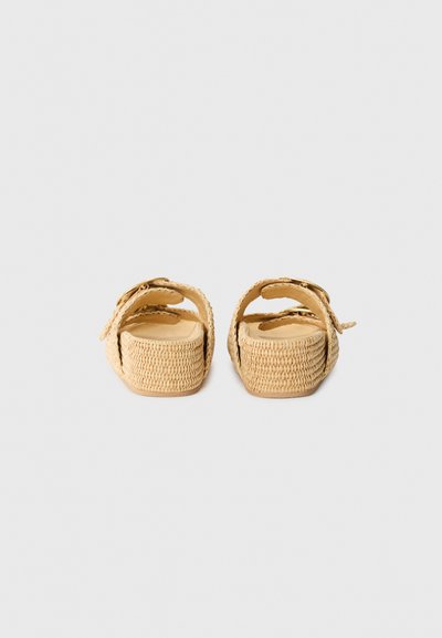 Sandales tissées beiges avec semelles plates et texturées, et brides réglables, dotées d'un embout rond et d'un design décontracté. Sans ornementation.