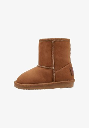 Bota corta de ante marrón con suela gruesa y costuras visibles, diseñada para clima frío y uso casual.