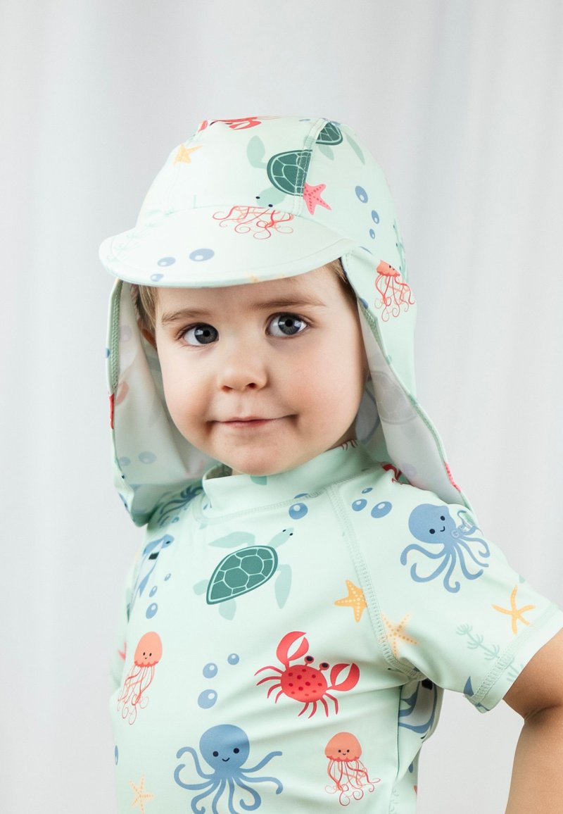 Hellgrün mit Sonnenhut und Rashguard für Kinder, versehen mit bunten Mustern maritimer Lebewesen, einschließlich Schildkröten, Kraken und Krabben.