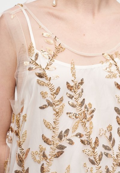 Διακοσμημένο διάφανο τοπ με χρυσά λουλουδάτα παγιέτες σε ελαφρύ ύφασμα, με λεπτές τιράντες και άνετη σιλουέτα.