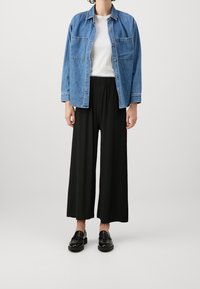 Ljusblå denimskjorta med två bröstfickor och knäppning. Svarta vida byxor med elastisk midja. Svarta läder loafers.