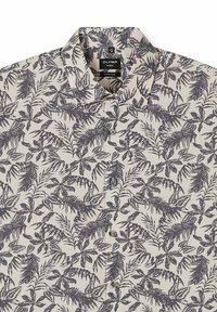Beige Knopfleiste-Hemd mit schwarzem tropischem Blattmuster, klassischem Kragen und schwarzem Markenlabel am Halsausschnitt.