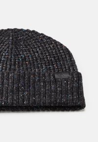 Gorro de malha preto com textura canelada, apresentando pontos coloridos por toda a parte e um pequeno patch de logotipo preto na dobra da bainha.