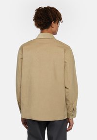 Beige katoenen shirt met een puntkraag, knoopmanchetten en een rechte zoom, met een gestructureerd uiterlijk en een minimalistisch ontwerp.