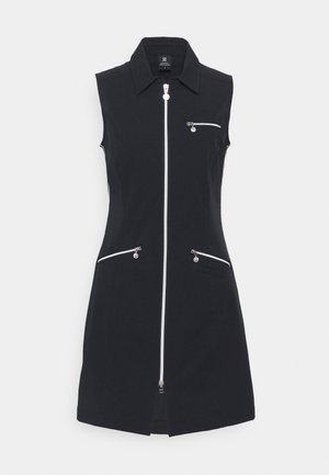 Robe noire sans manches avec un col et une fermeture éclair argentée à l'avant, dotée de trois poches zippées, présentée sur un fond blanc uni.
