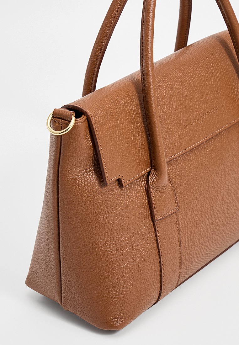Braune Lederhandtasche mit strukturiertem Finish, zwei Griffen, einem Klappenverschluss und minimalem Zubehör. Besitzt ein seitliches Ringdetail.