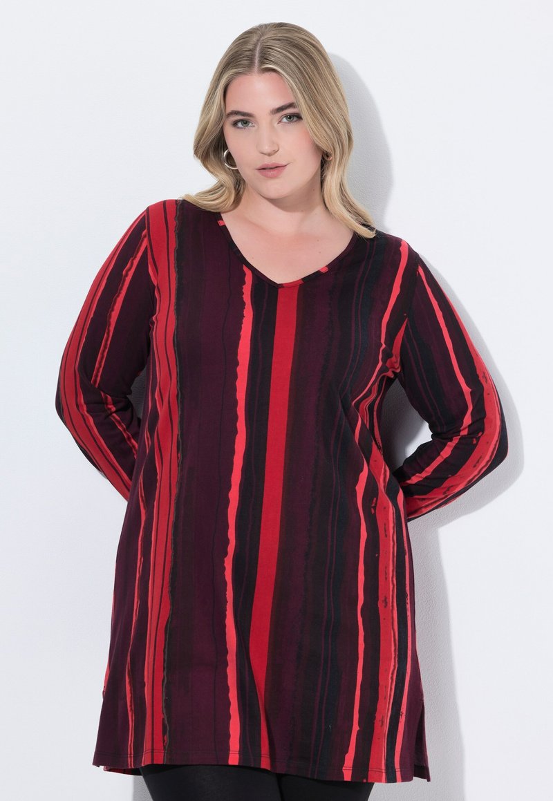 Long-sleeve tunic with a V-neck, featuring vertical red and black stripes on a dark background. Soft fabric with a relaxed fit and side slits.