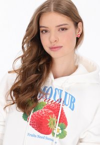 Fehér kapucnis pulóver eper grafikával, kék szöveg "Fruits Club" felirattal és húzózsinórokkal; sima textúra, élénk színű dizájnelemekkel.