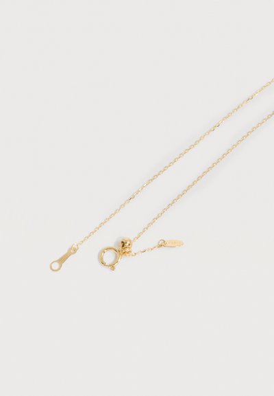 Λεπτό χρυσό κολιέ με στρογγυλό κούμπωμα ελατηρίου και μικρό οβάλ μενταγιόν χαραγμένο με τη λέξη "ΠΑΡΙΣΙ" σε ανοιχτό φόντο.