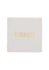Vit kvadratisk platta med ordet "amor" i guldprickade gemena bokstäver centrerat på den.