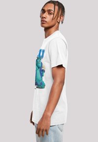 White cotton T-shirt featuring a large graphic of a blue monster in a varsity jacket, highlighted by blue text reading "MU" above.